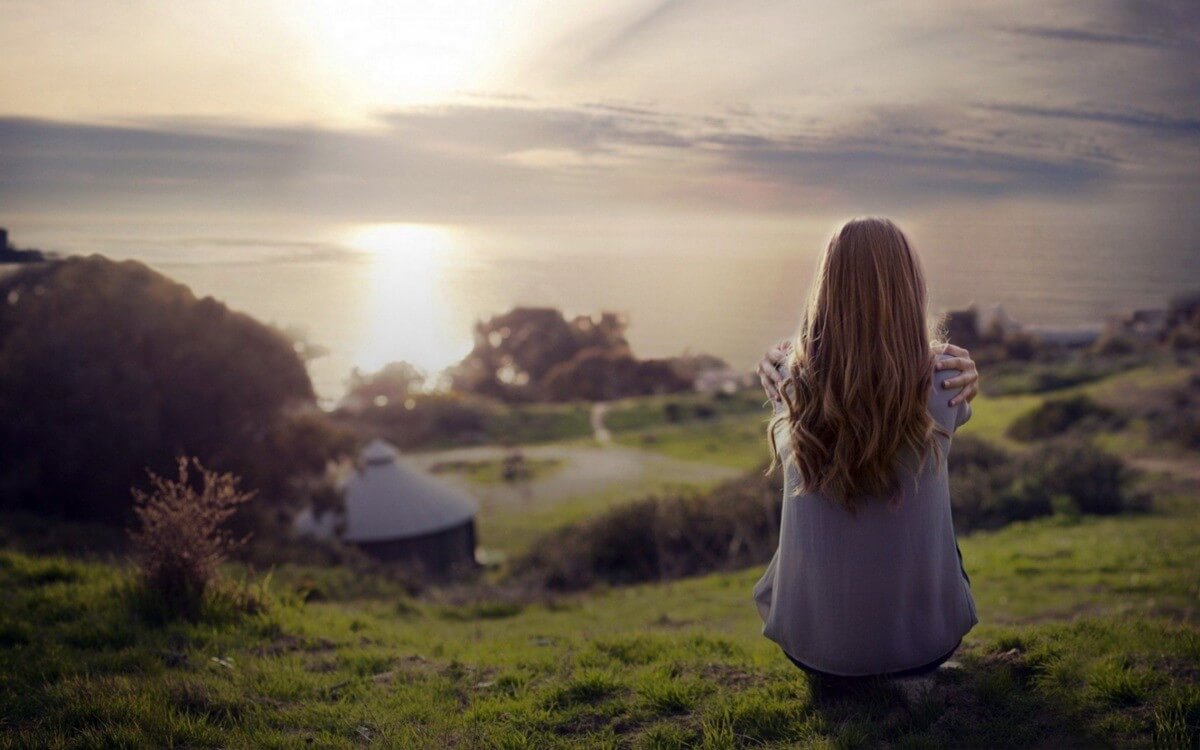 Mulher sentada olhando para o horizonte